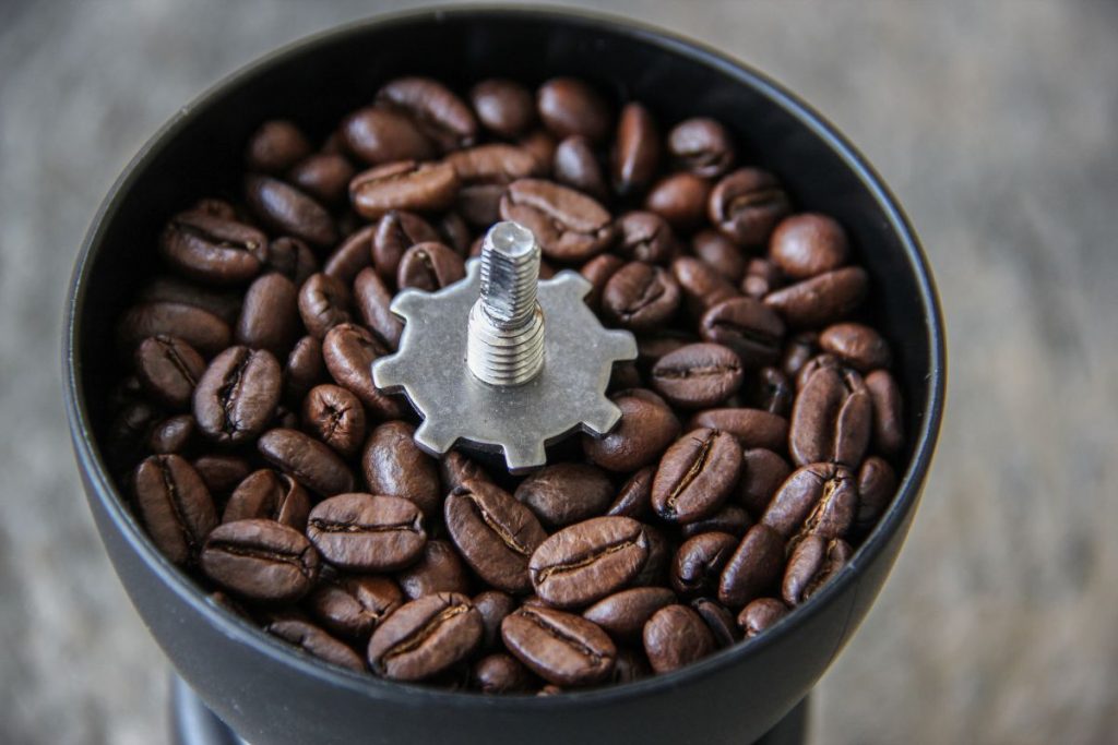 Arabica Dark roasted Coffee beans in a hand grinder