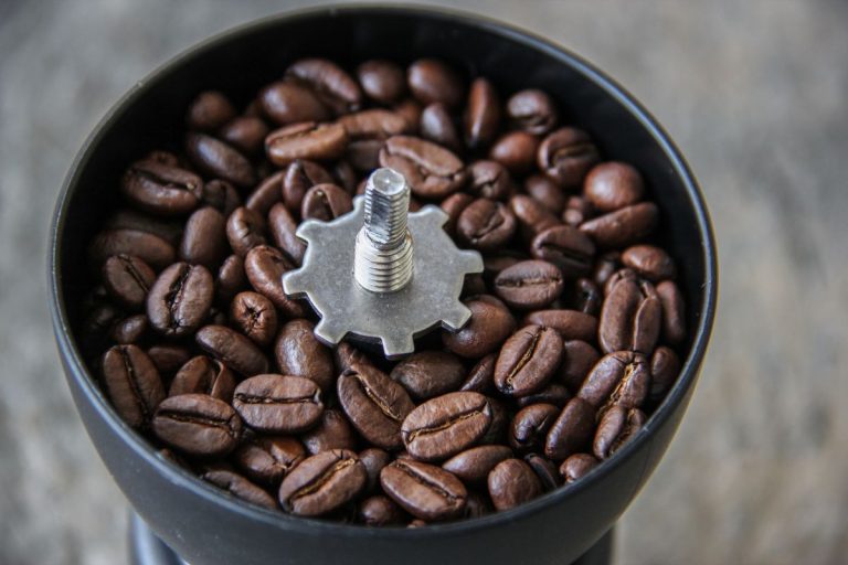 Arabica Dark roasted Coffee beans in a hand grinder
